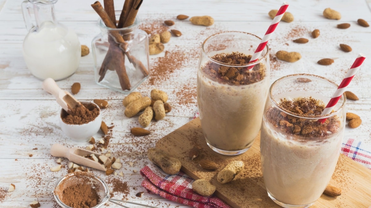 Peanut and almond butter banana oat smoothie with paper straws on a wooden rustic table