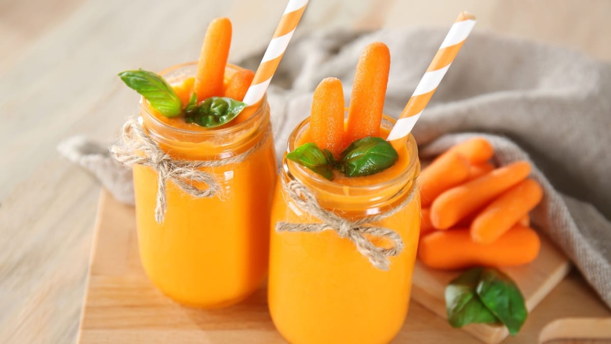 Glass jars with carrot smoothie on wooden table