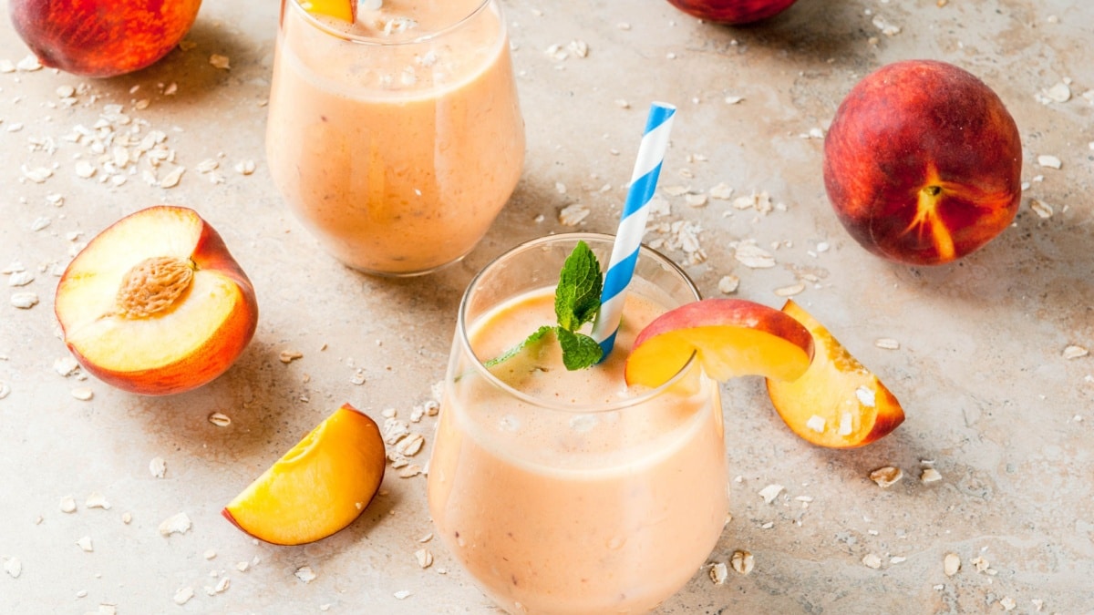 Healthy eating. Breakfast, snack. Drink smoothies from fresh peach, milk (yogurt) and oatmeal, decorated with mint leaves, with striped straws. On a light stone table.