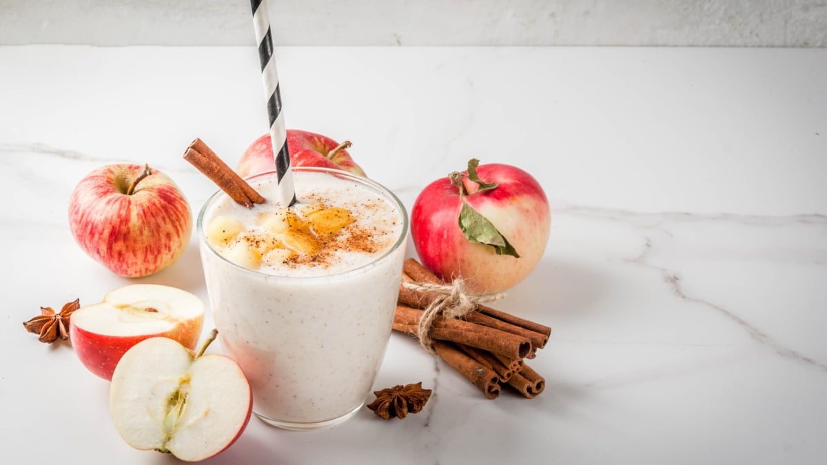 Healthy vegan food. Dietary breakfast or snack. Apple pie smoothies, with apples, yogurt, cinnamon, spices, walnuts. In a glass, on a white marble table.