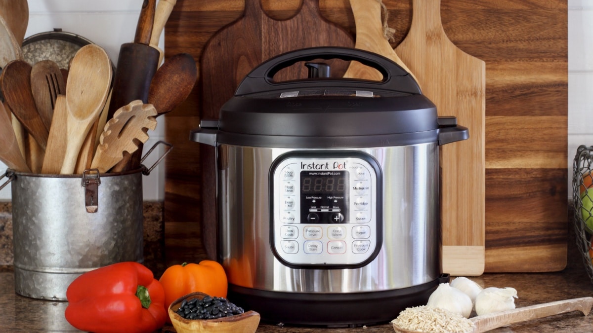 Instant Pot pressure cooker on kitchen counter with beans and rice.