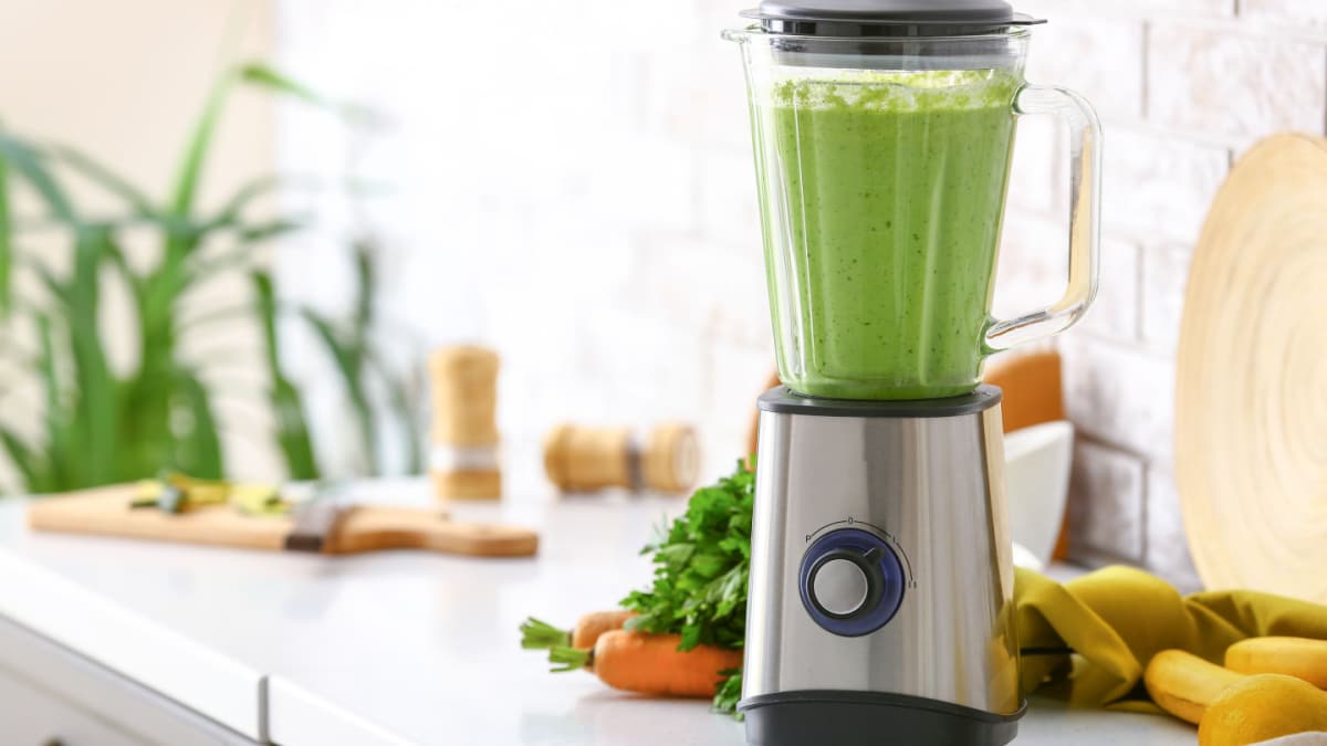 Blender with healthy smoothie and ingredients on table in kitchen