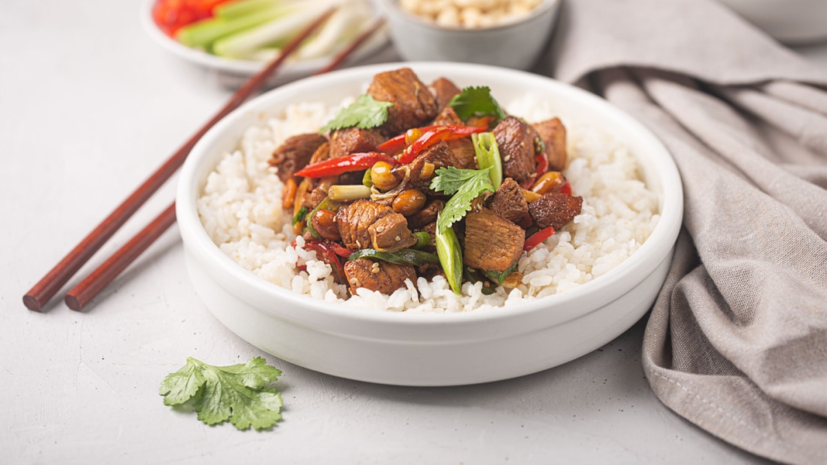 Kung pao or kung po, traditional chinese food prepared with chicken, beef or pork meat, sometimes sea food, with rice as a side dish, concrete background