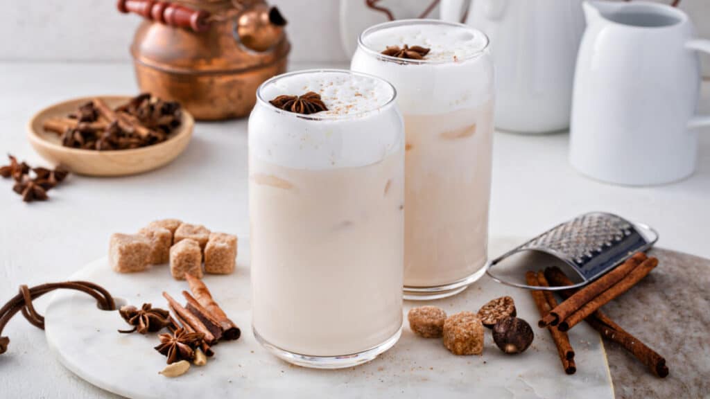 Iced chai latte with warm winter spices topped with milk foam, indian tea drink